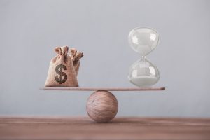 Financial concept : Write sand clock or hourglass symbol and dollar bags on a balance scale in equal position.Time value of money, asset growth over time, investment in long-term equity for more money